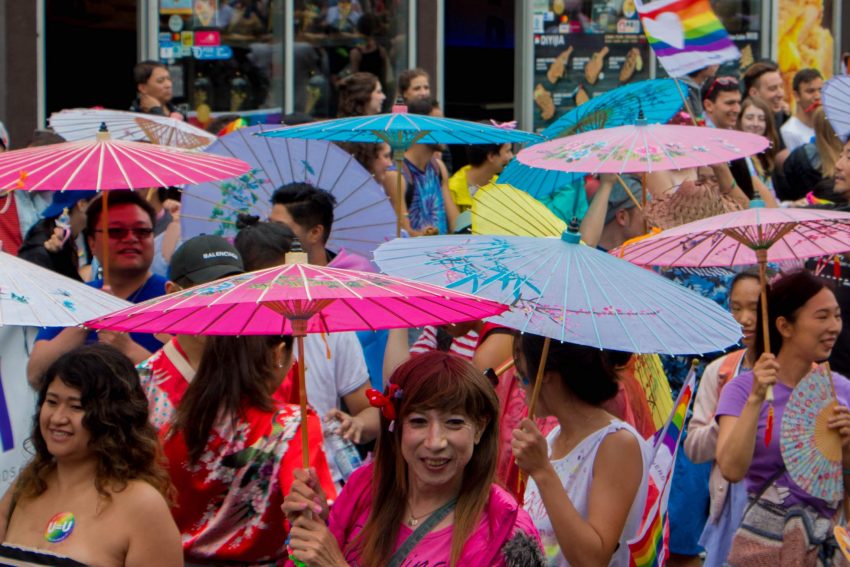 By Asha Collins, Parade Day; June 24 - Parade participants in the the South East Asian group walking with traditional oil-paper umbrella show off their honour, flare, and support in promoting awareness of the diversity of LGBTQ2+ folks in Pride. 