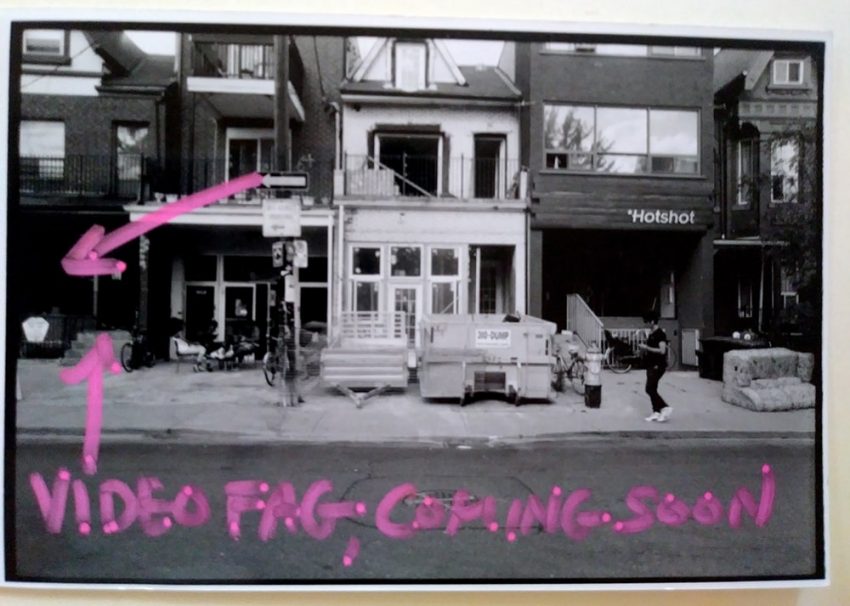Black and white photograph of street in Kensington Market, with pink arrows drawn on top with the words “Videofag, coming soon”