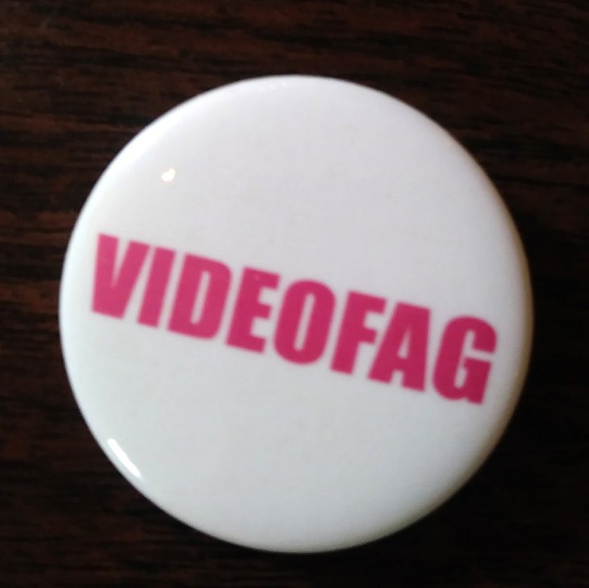 White button with “Videofag” written in pink lettering