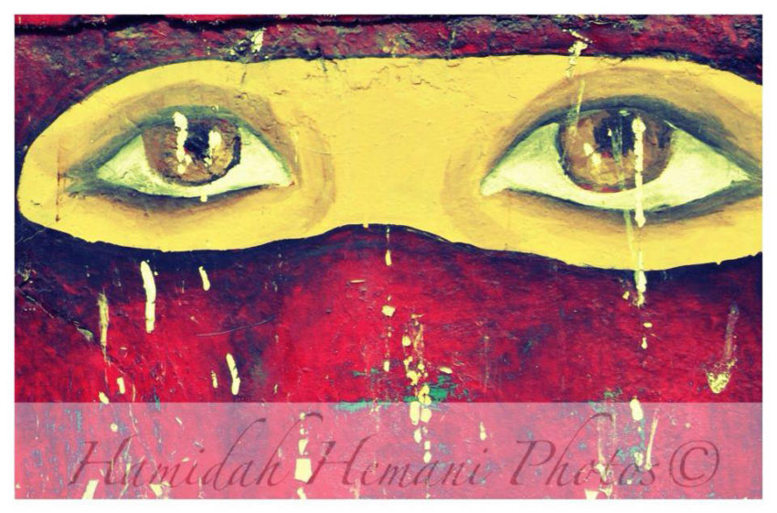 Hemidah Hemani photograph of a painting of eyes painted yellow peering at the viewer. © Hemidah Hemani