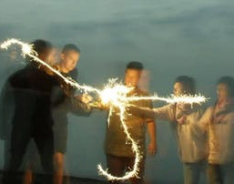 Group of 5 people on a beach waving sparklers