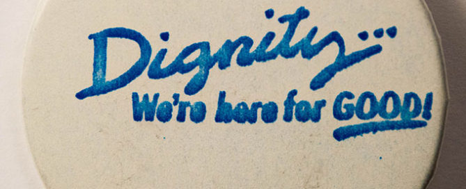 White button with blue text reading “Dignity: We’re here for GOOD!”