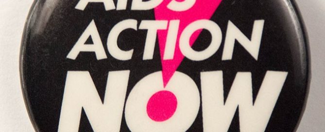 Black button with white text reading, “AIDS Action Now!” in all caps. The exclamation mark is an inverted hot pink triangle with a hot pink dot at the bottom point.