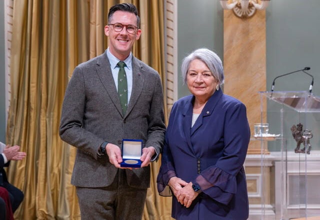A man holds an award smiling next to a woman.
